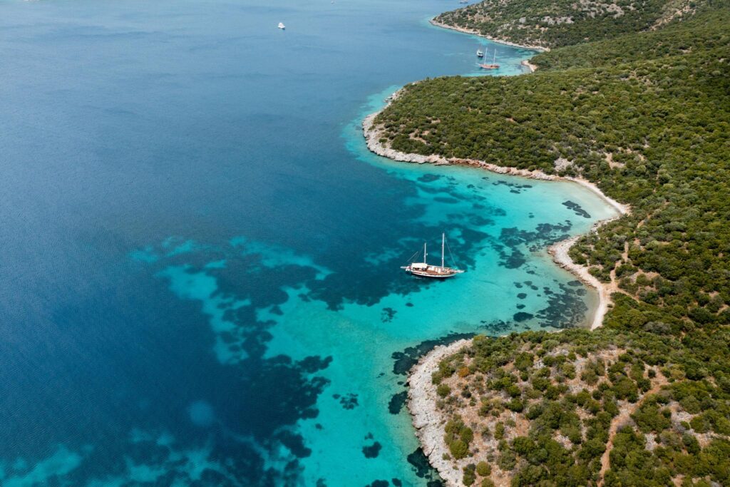 Aerial view of a turquoise bay along the Bozburun coastline, with a gulet anchored near shore
